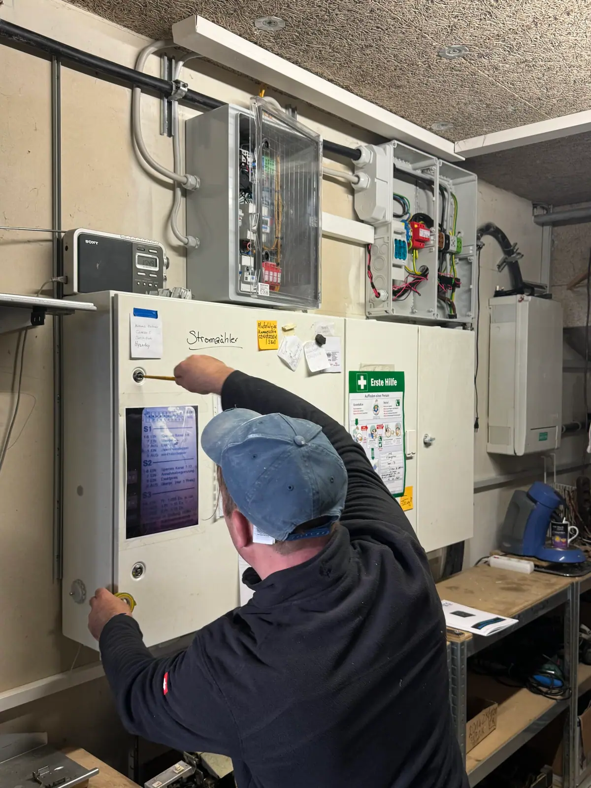 Elektriker von enerbloc arbeitet an einem Schaltschrank, von hinten fotografiert