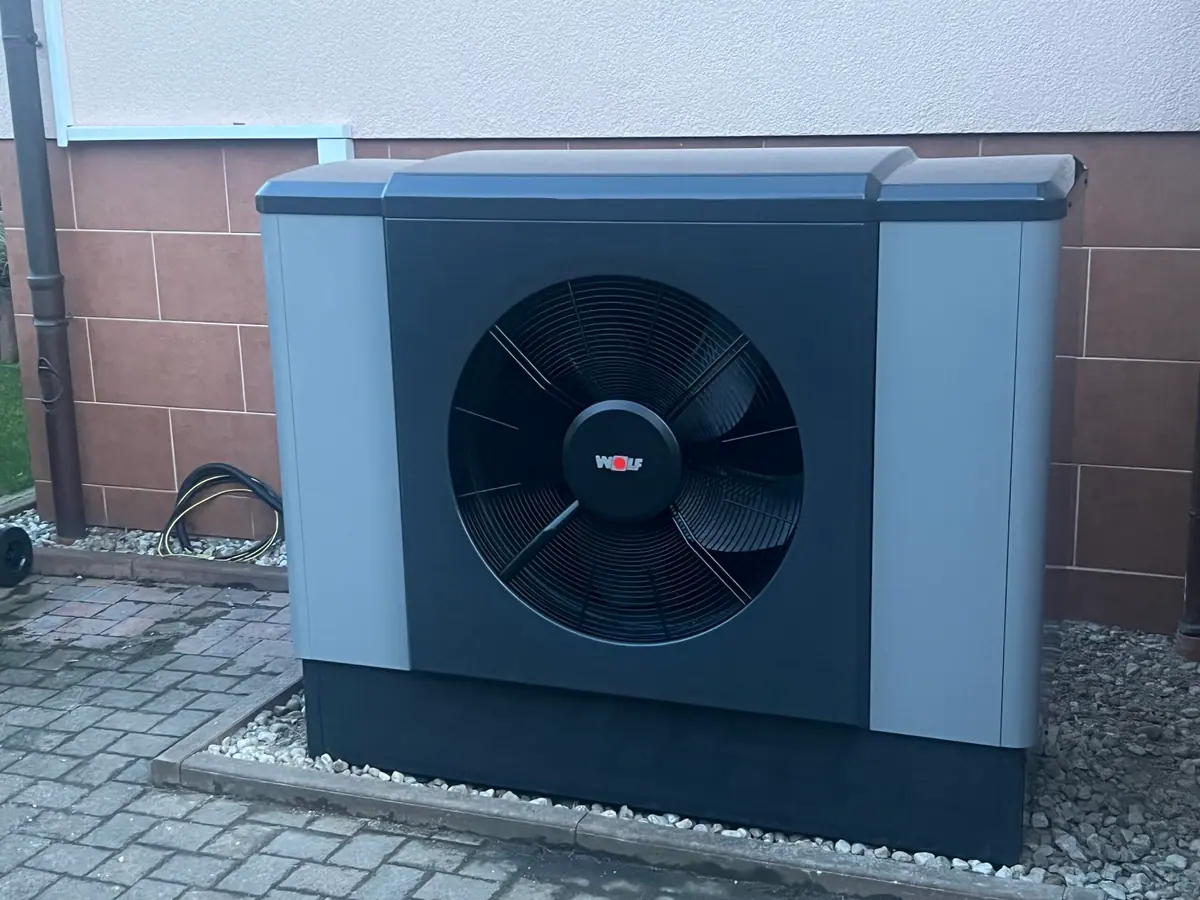 Außeneinheit einer Luft-Wasser-Wärmepumpe auf einem Kiesbett vor der Hauswand